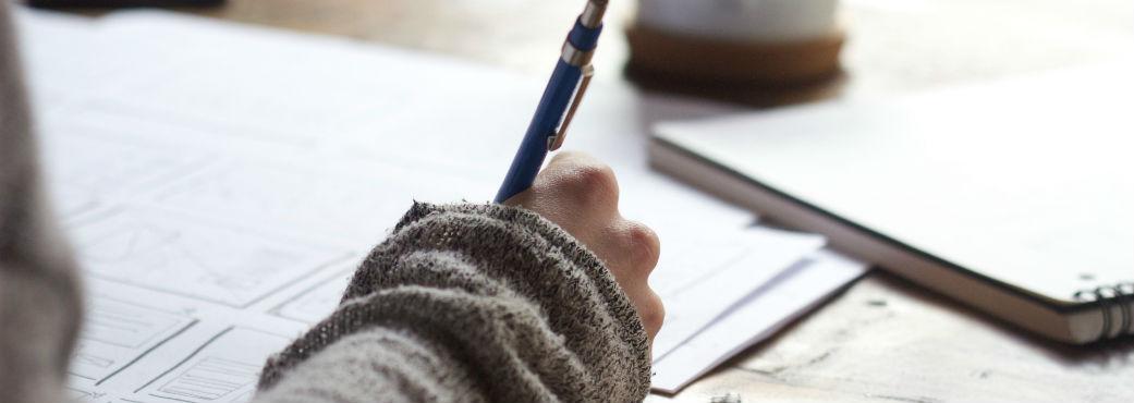 Hand holding pen writing on paper