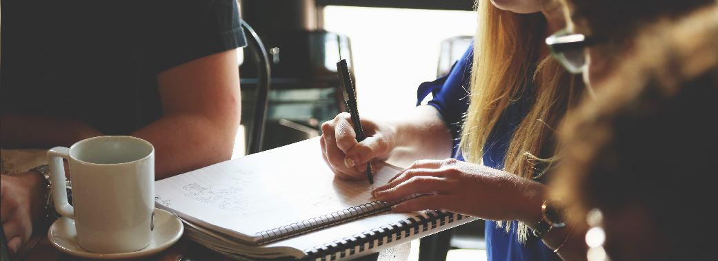 Three people at table, someone taking notes