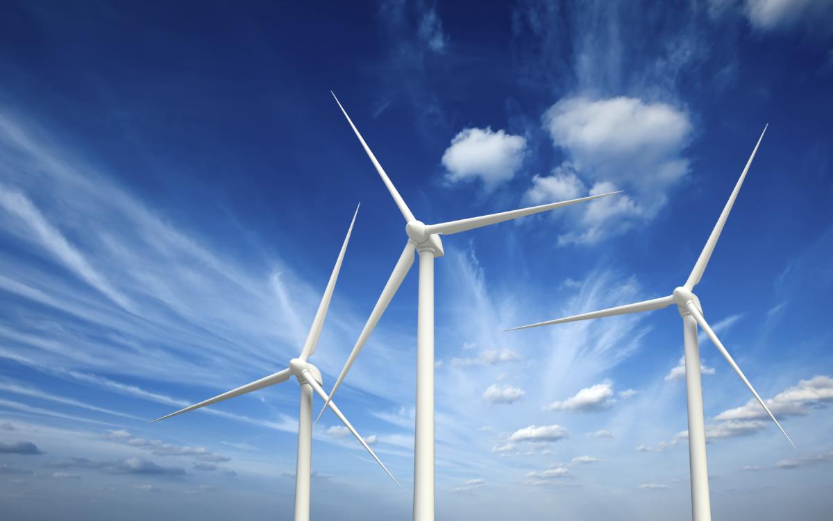 Image of three wind turbines with a bright blue sky behind them