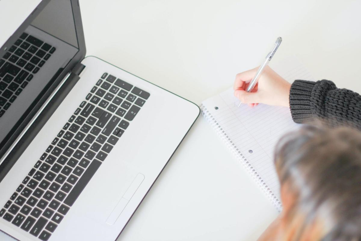 Woman looking at laptop taking notes