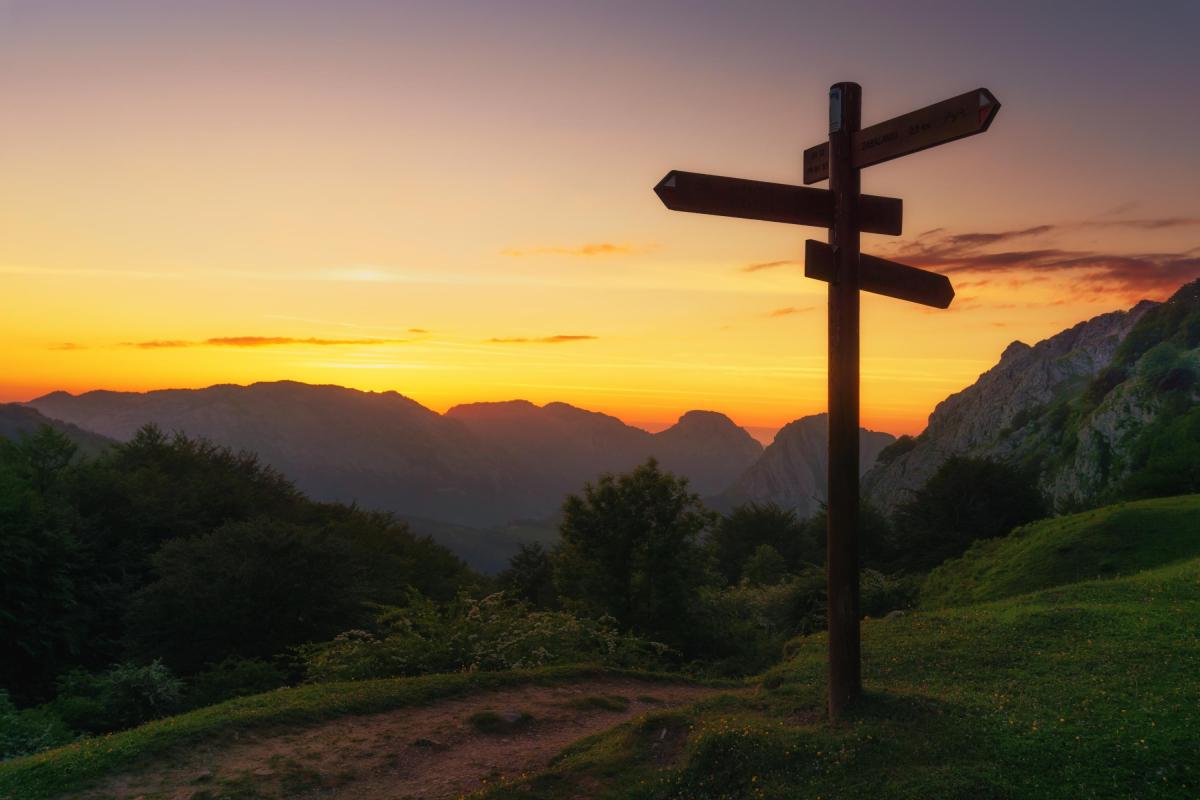 A signpost with mountains and a sunset in the background