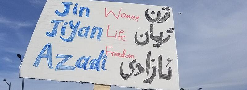 Shows placard from woman life freedom protest