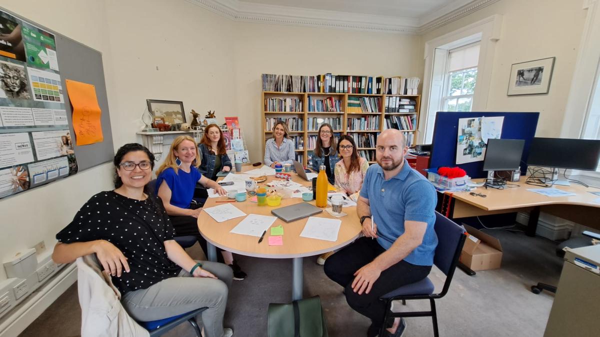 Seven centre members sit around a meeting table in the CHRCE office.