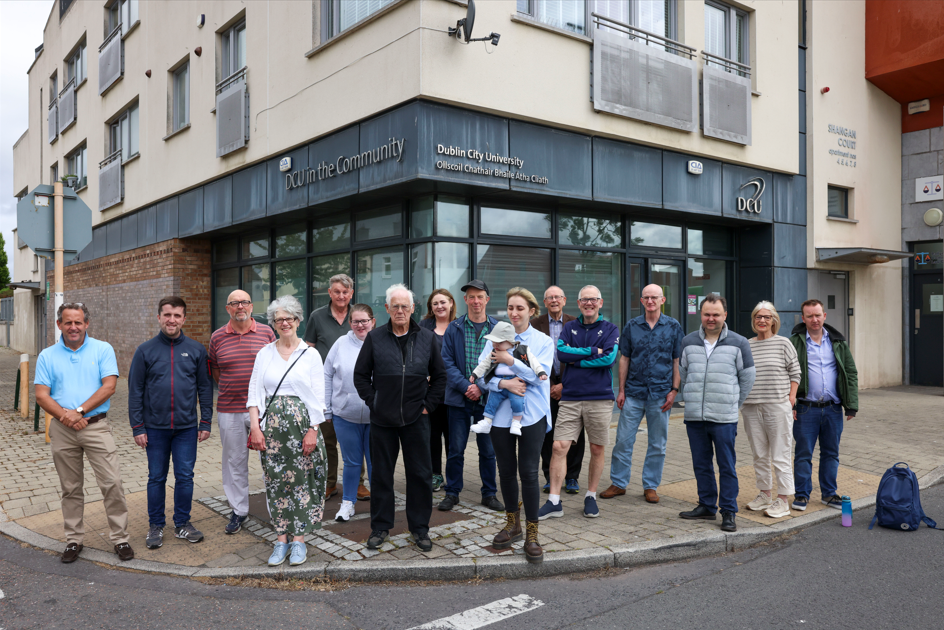A group of people posing for a photo in front of DCU in the Community building