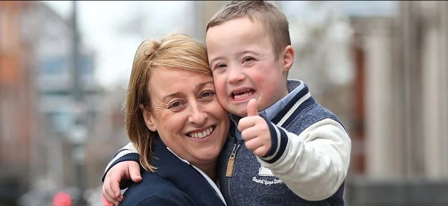 A person and a child with Down Syndrome smiling