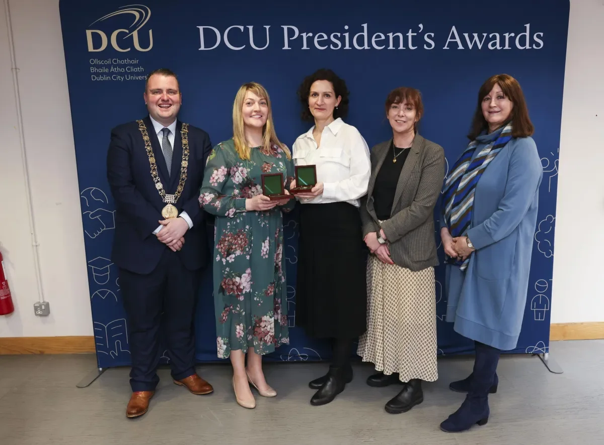 An image of the President's Award for Engagement winners in front of a DCU branded backdrop