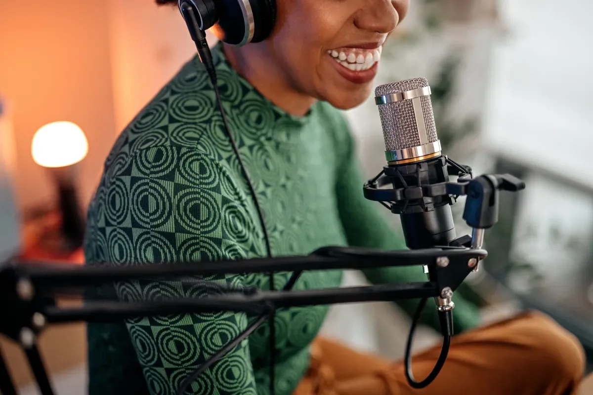 Shows woman speaking into podcasting microphone