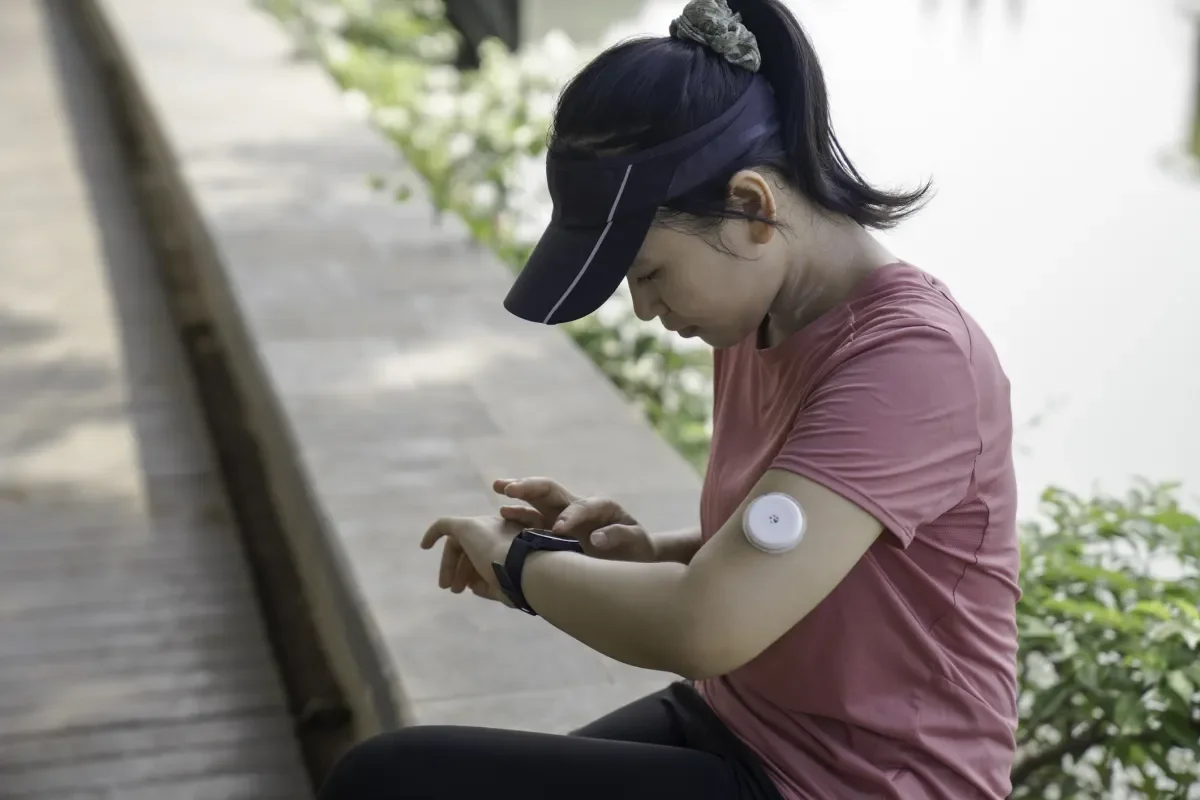 Shows a young woman using a smart watch to access data from a sensor on her arm