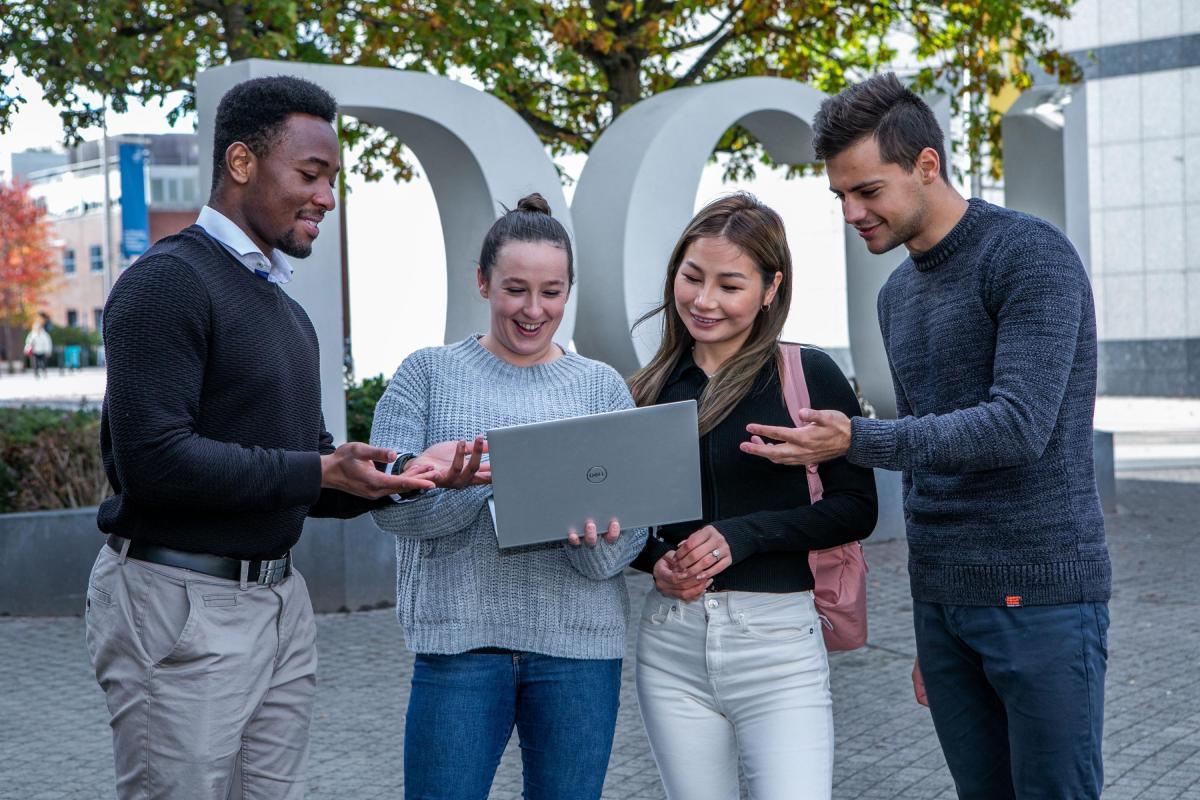 Students standing in front of the DCU sign.