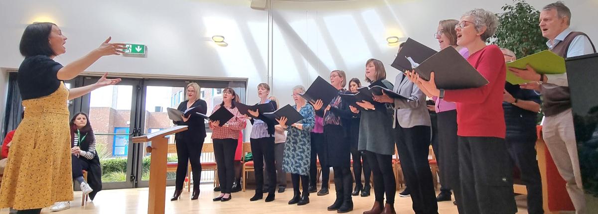 Choir performers singing in a line while all holding choir books