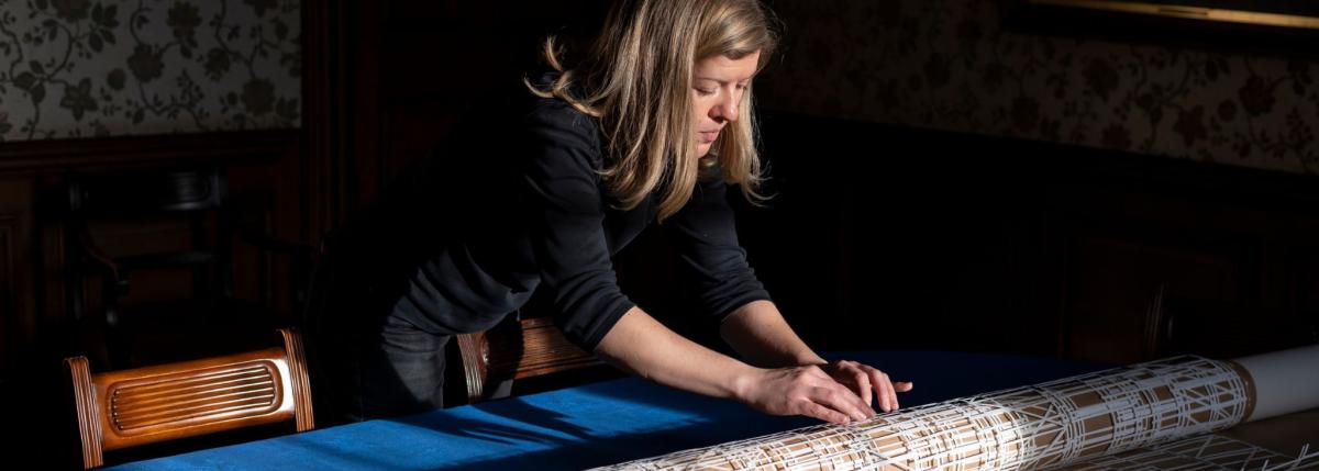 Susan Leen - Visual Artist in Residence at DCU carefully rolls up a laser cut piece of paper around a brown tube