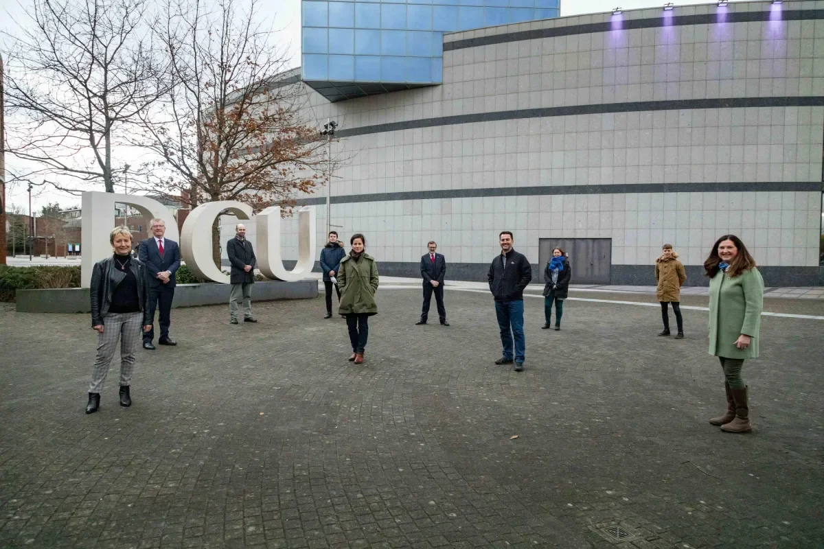 10 people standing in front of dcu sign