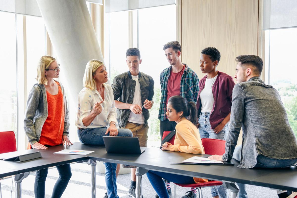 lecturer speaking to a small group of students gathered around a table