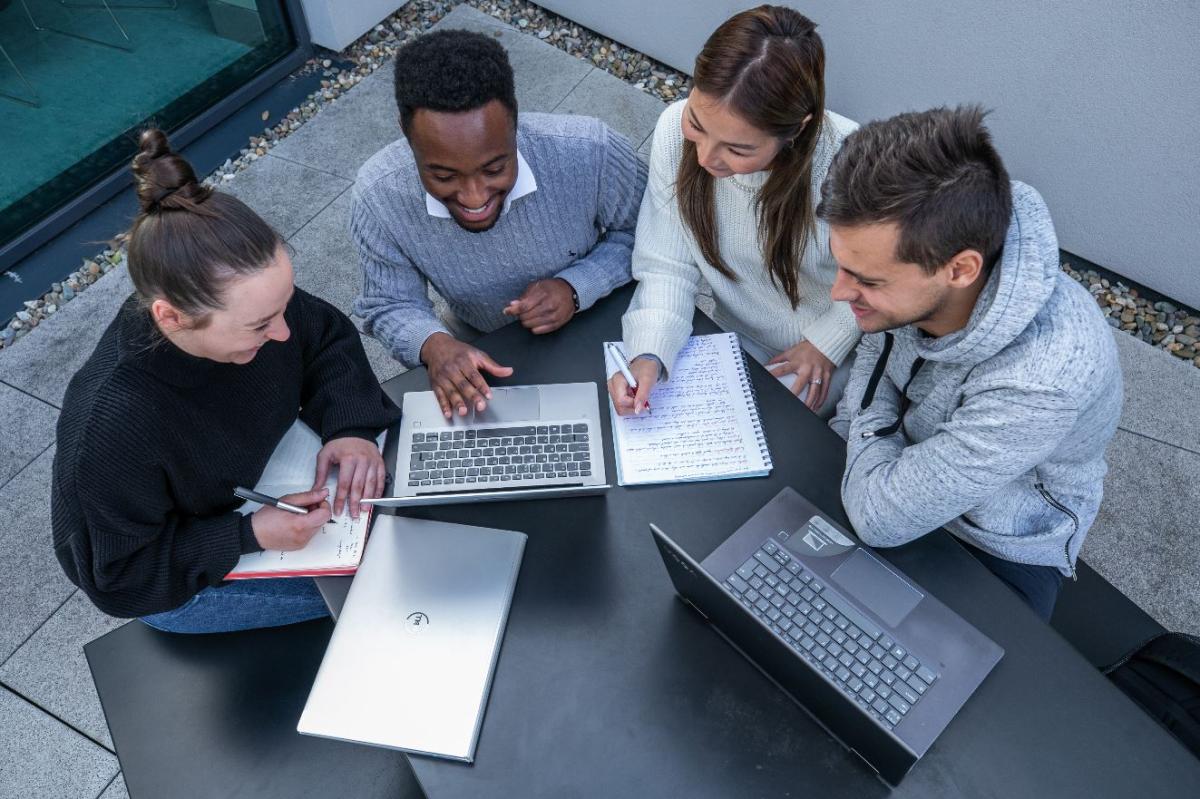 An image of four students working on laptops.