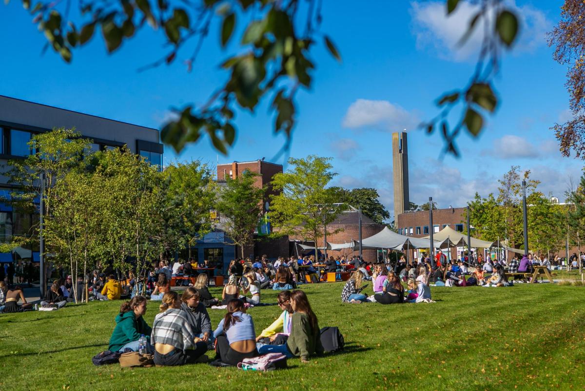 Image shows students sitting outside