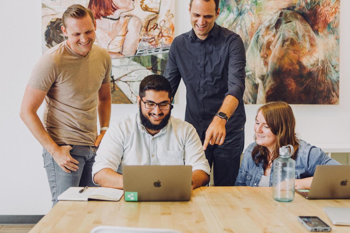 A group of staff working at a laptop together