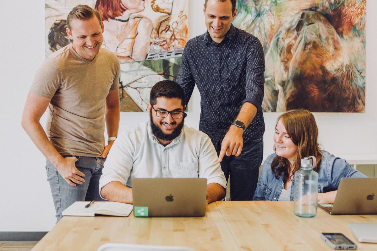 A group of staff working at a laptop together 