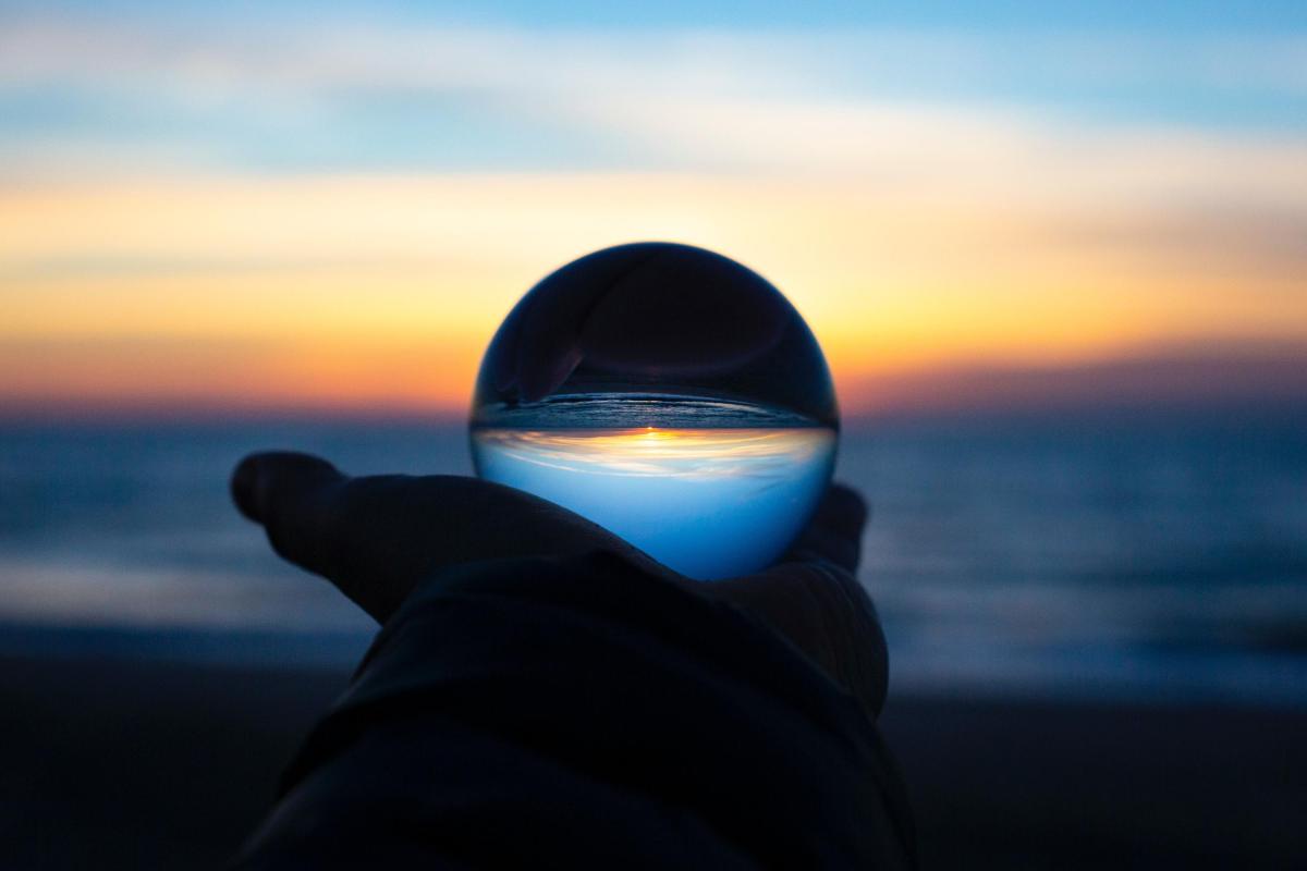 Hand with clear glass ball and horizon