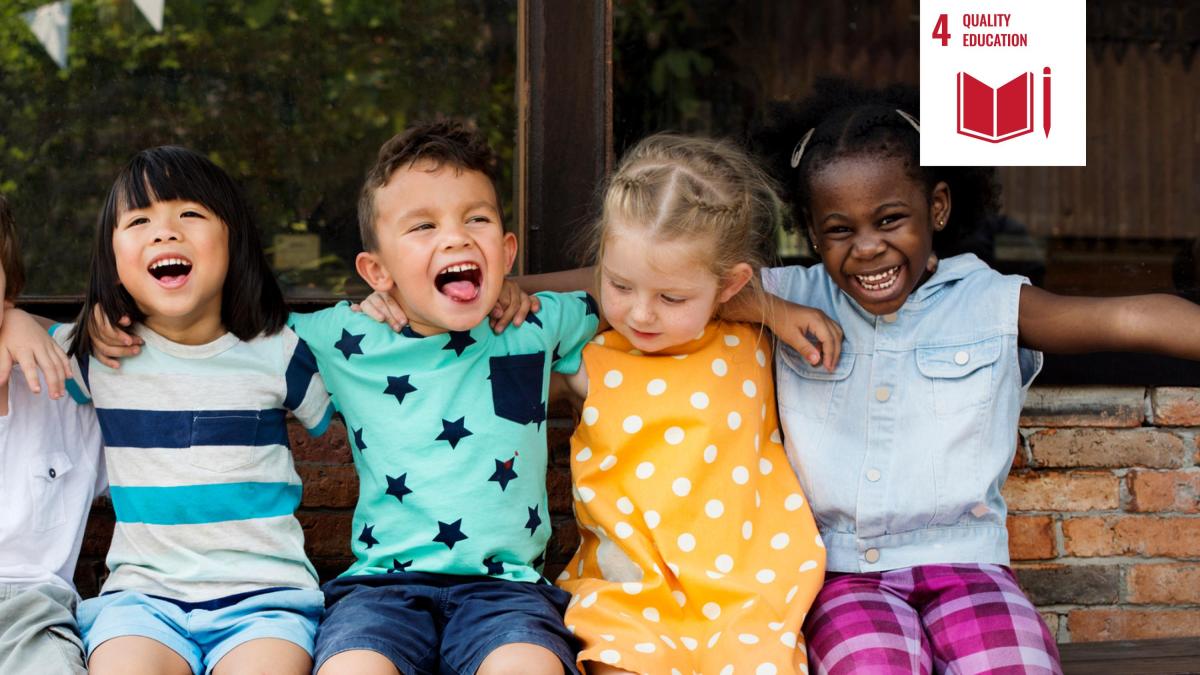 Shows children sitting on a bench arm in arm, smiling.