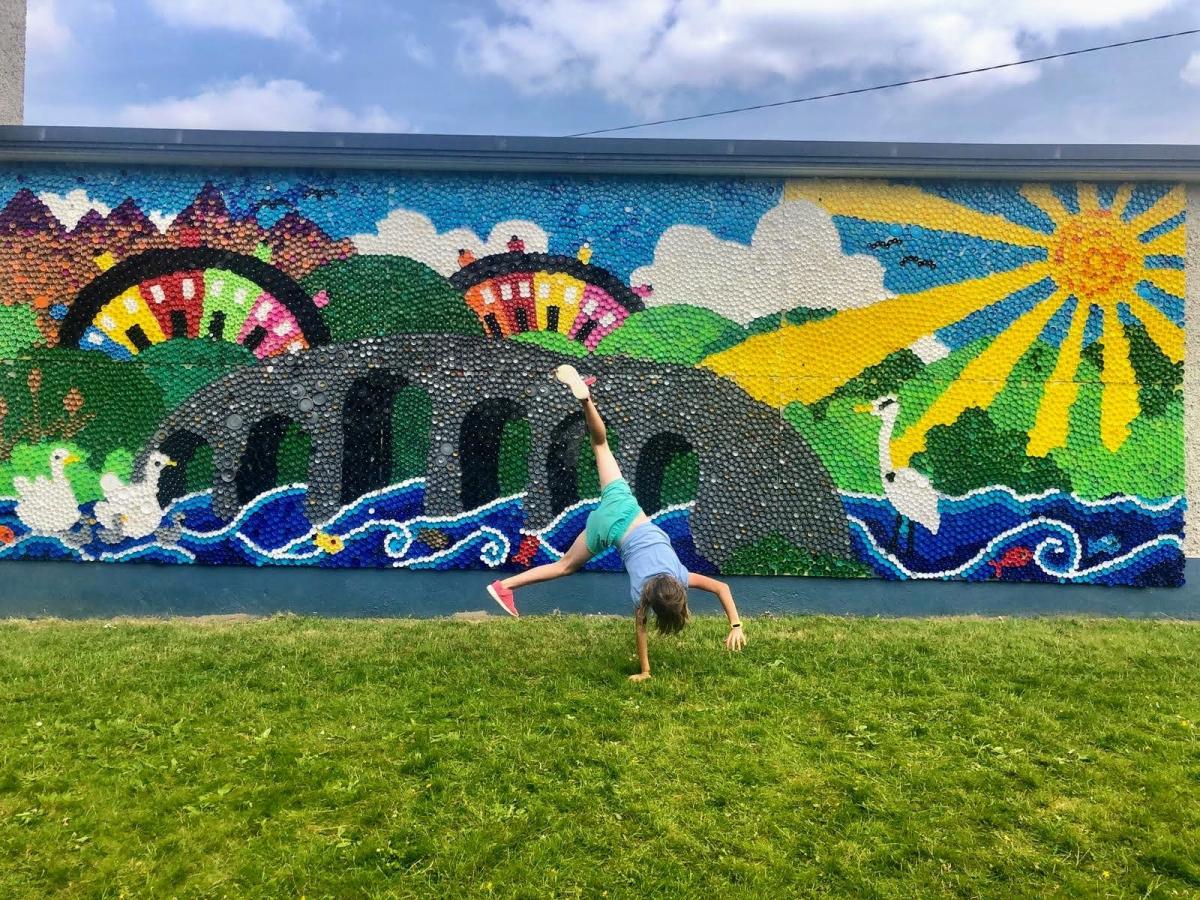 A student cartwheels in front of a mural
