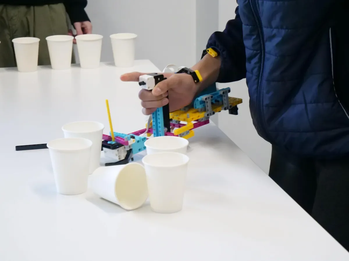 student testing out lifting a cup with their lego prosthetic arm