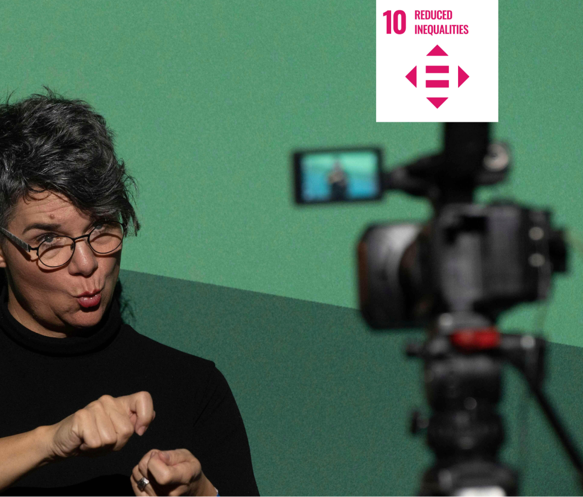 Shows a woman communicating in sign language as a camera films her with a white icon signifying UN Sustainable Development Goal ten