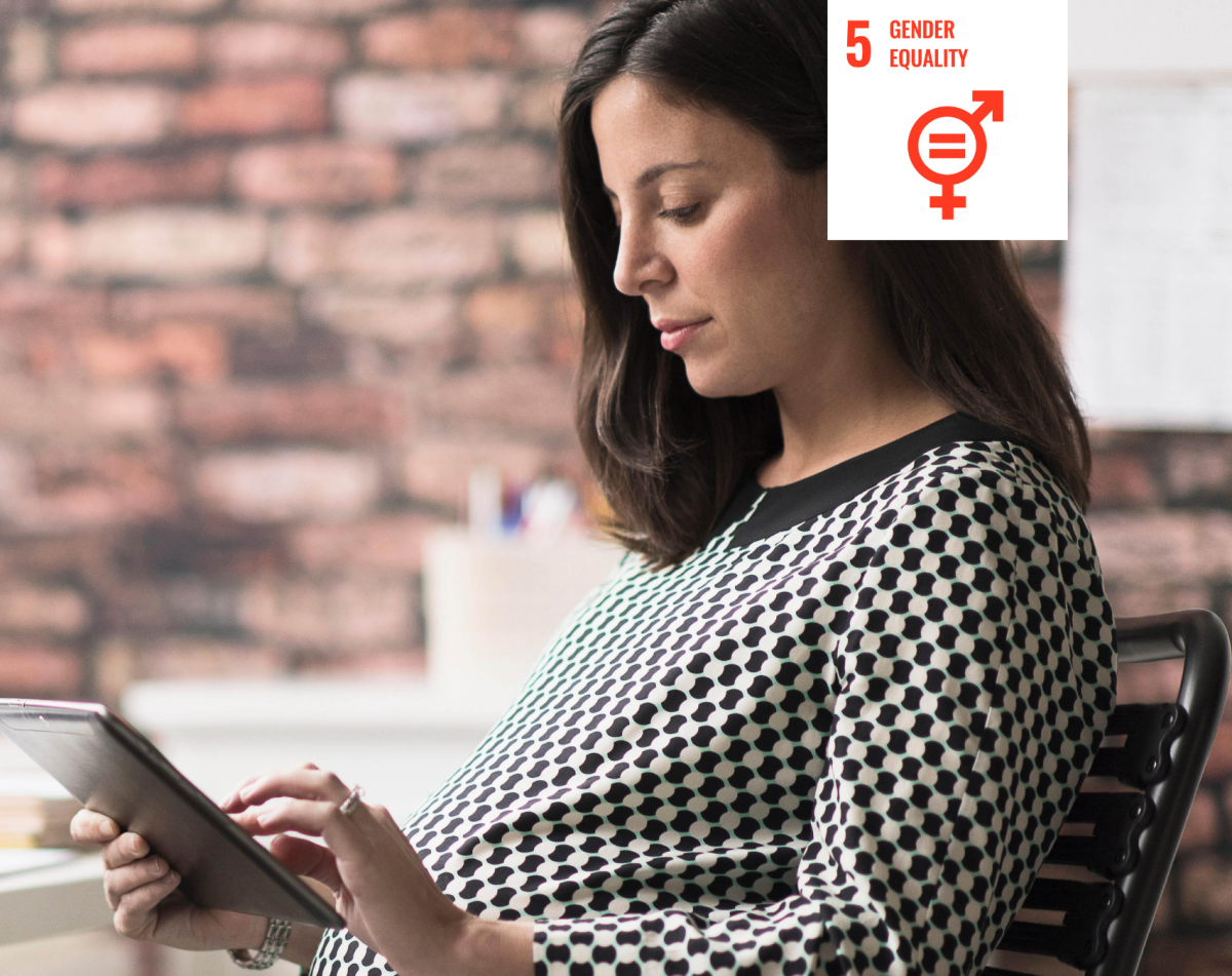 Shows a woman in an office using a digital tablet with a white icon signifying UN Sustainable Development Goal five