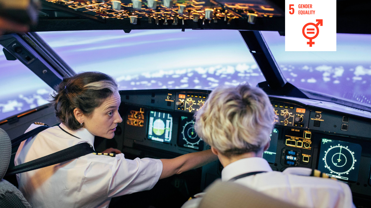 Shows two women piloting a commercial aircraft with a white icon signifying UN Sustainable Development goal five 