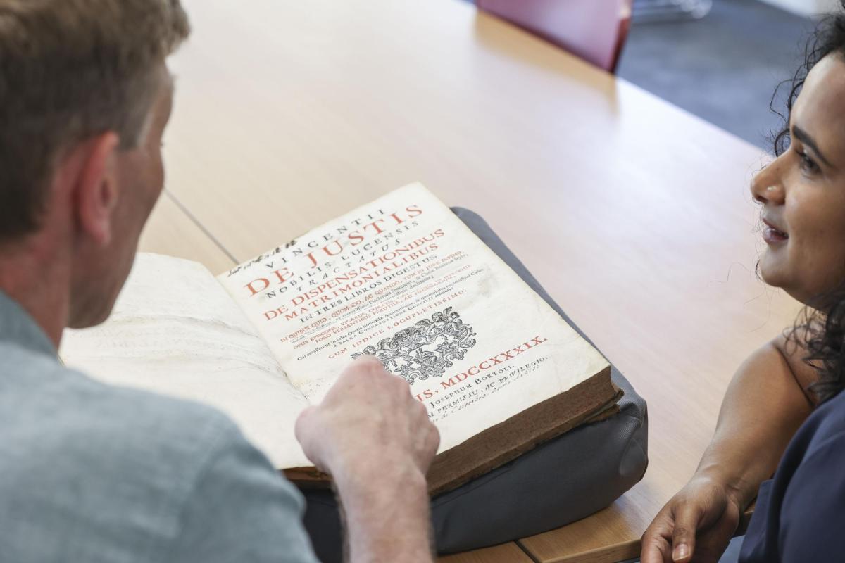 Shows researchers examining an archive text and discussing its contents