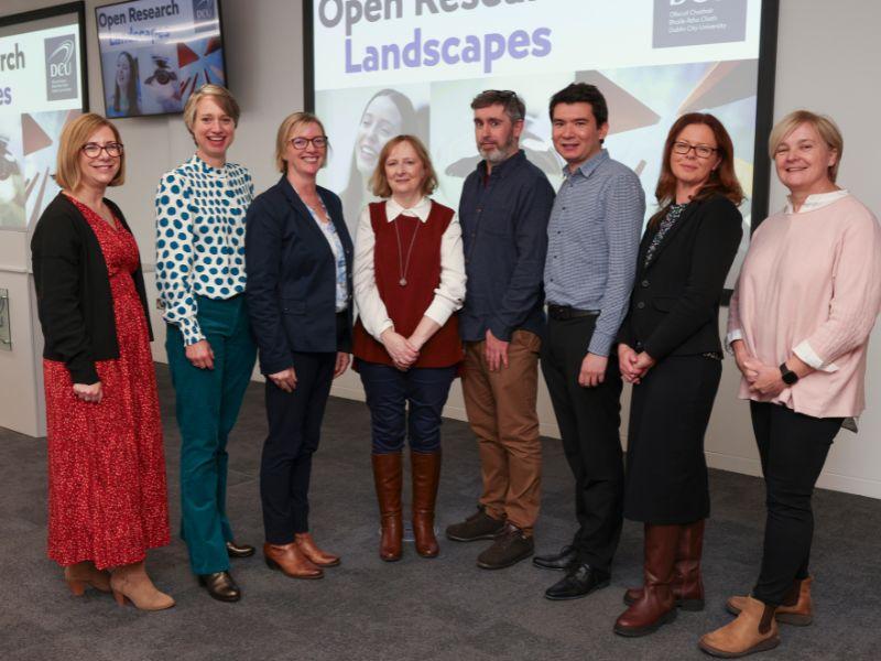 Shows a group of researchers, academics and administrative staff pose at a conference style academic event