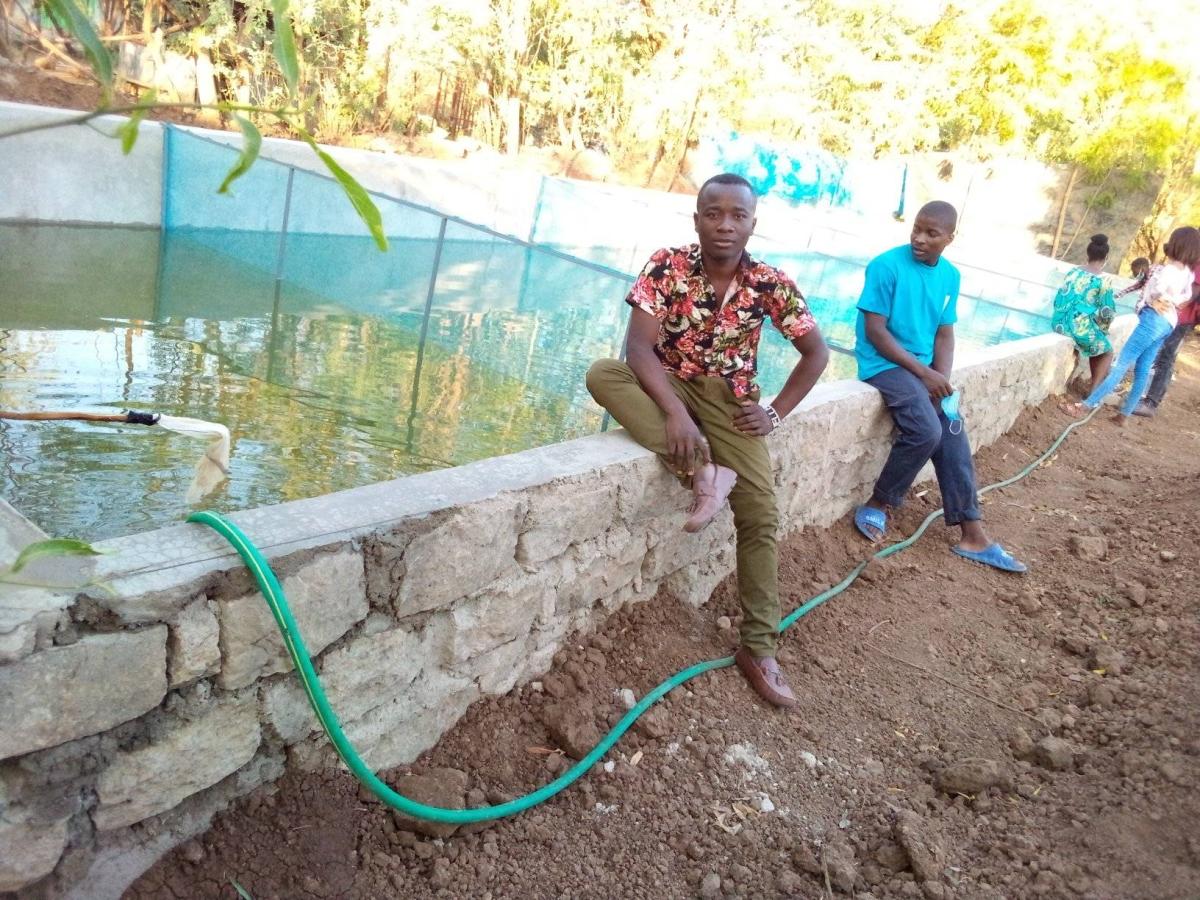 Shows members of the Vijana Twaweza next to the fish pond in Kakuma camp