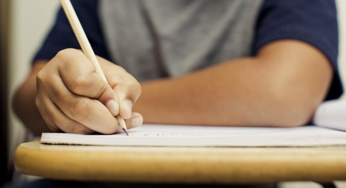 Shows close up of child using pencil to write in exercise book