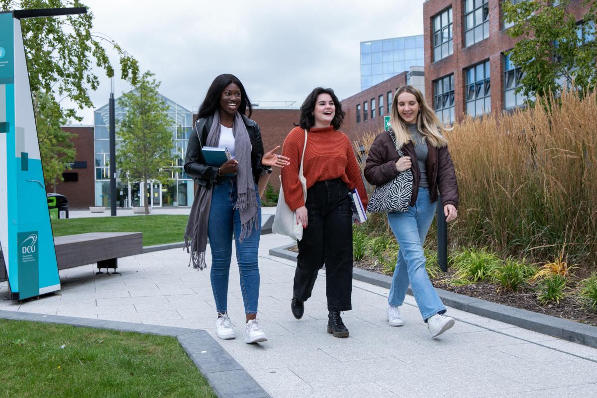 Image shows three students chatting and walking on campus