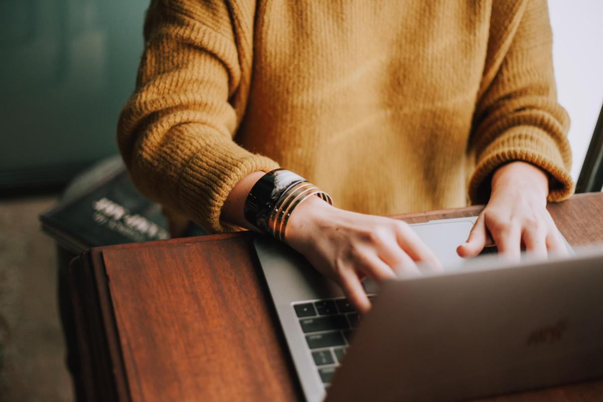 Person in a yellow jumper working at a laptop