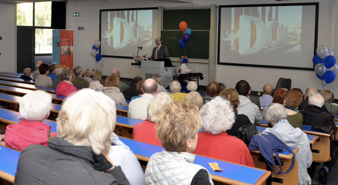 group of mature learners listen to a speaker in a lecture hall