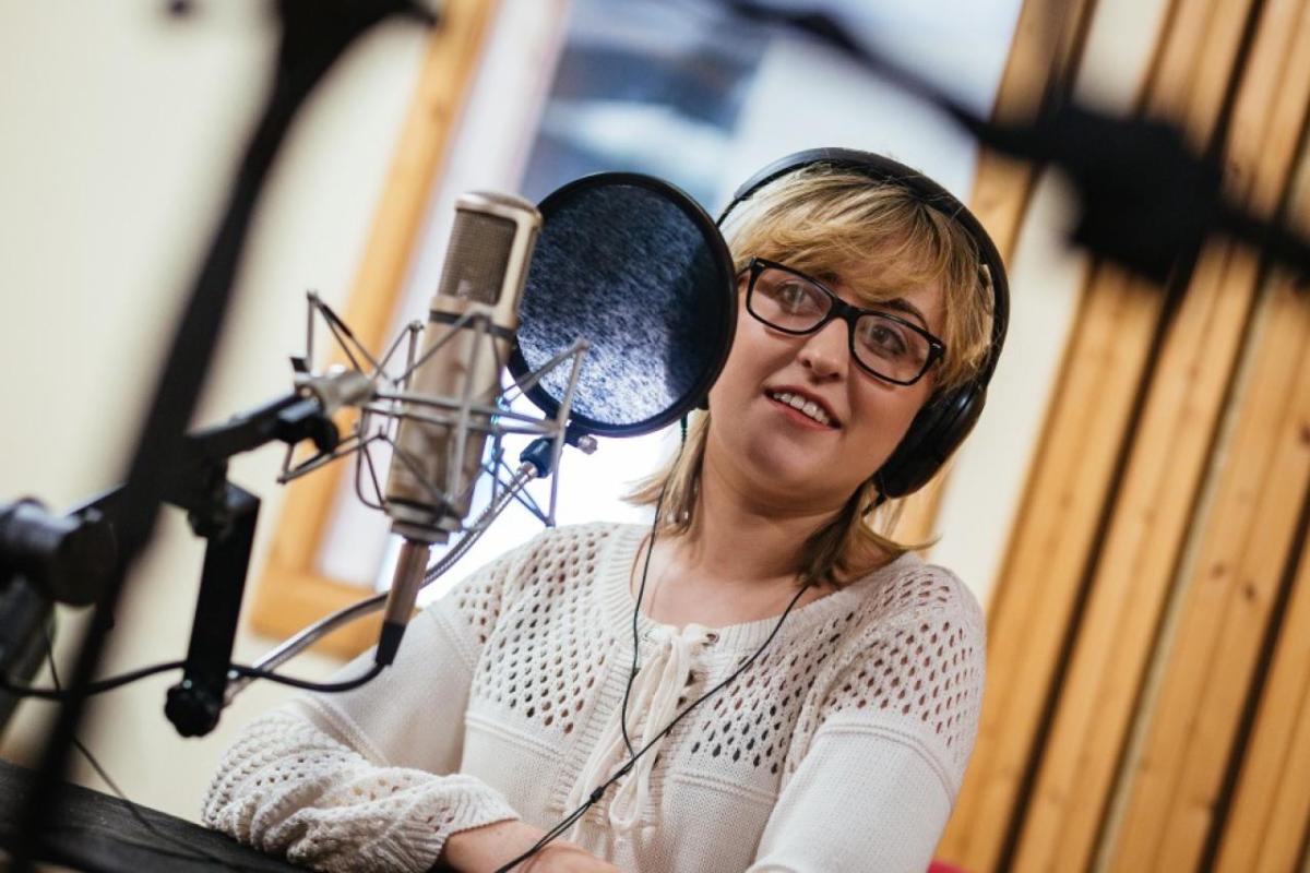 One student speaking into a microphone in a studio