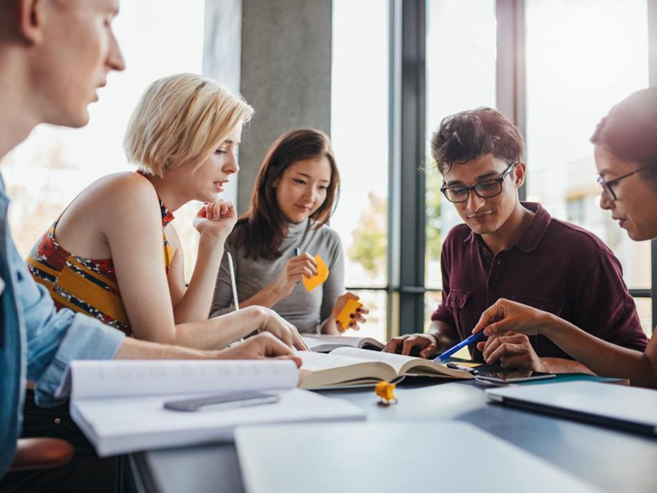 Five students collaborating at a desk