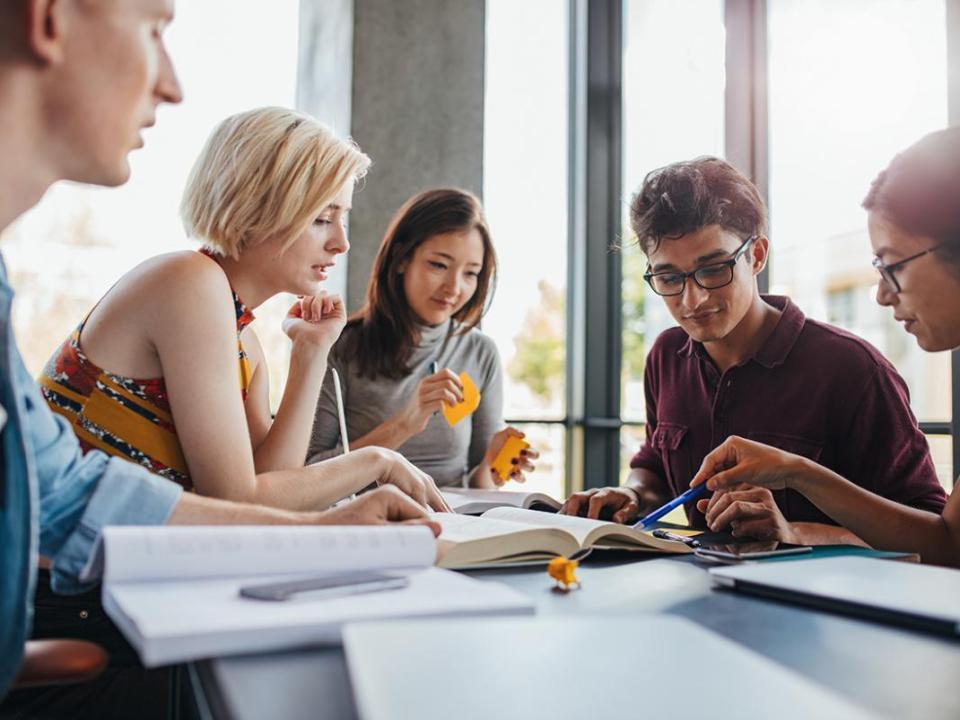 Five students collaborating at a desk 