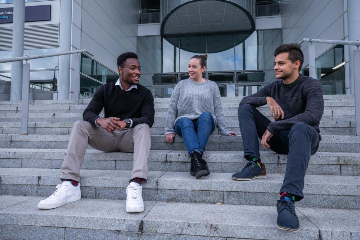 Three students sitting on steps chatting