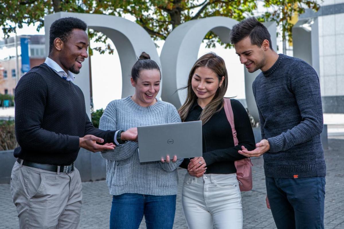Four students collaborating on DCU campus using laptops