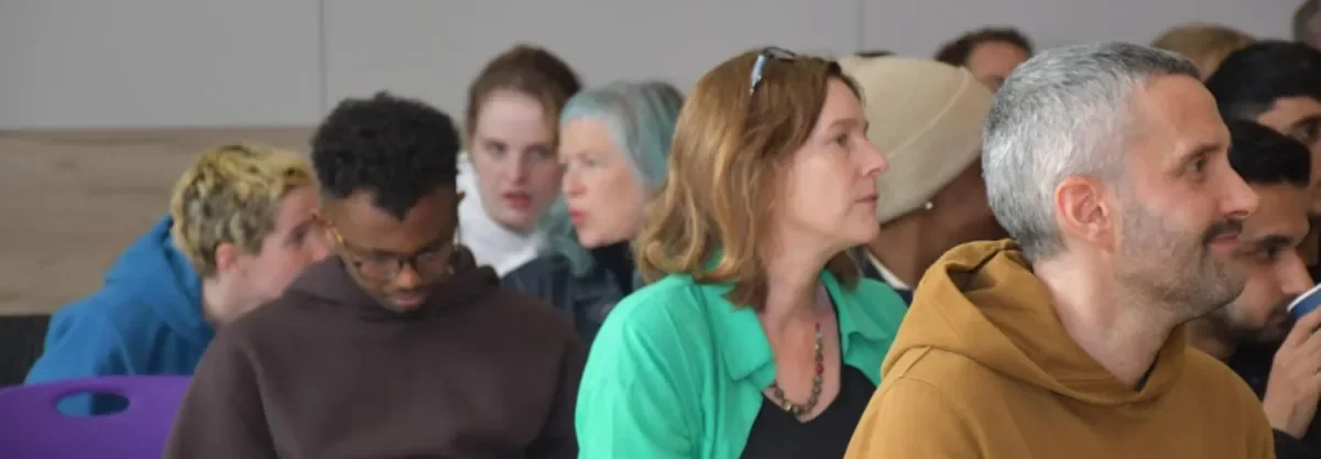 Men and women sitting in rows of seats listening and talking