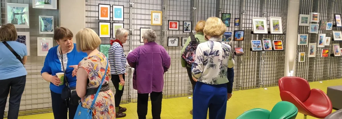 Selection of women standing, chatting and looking at the artwork they created 