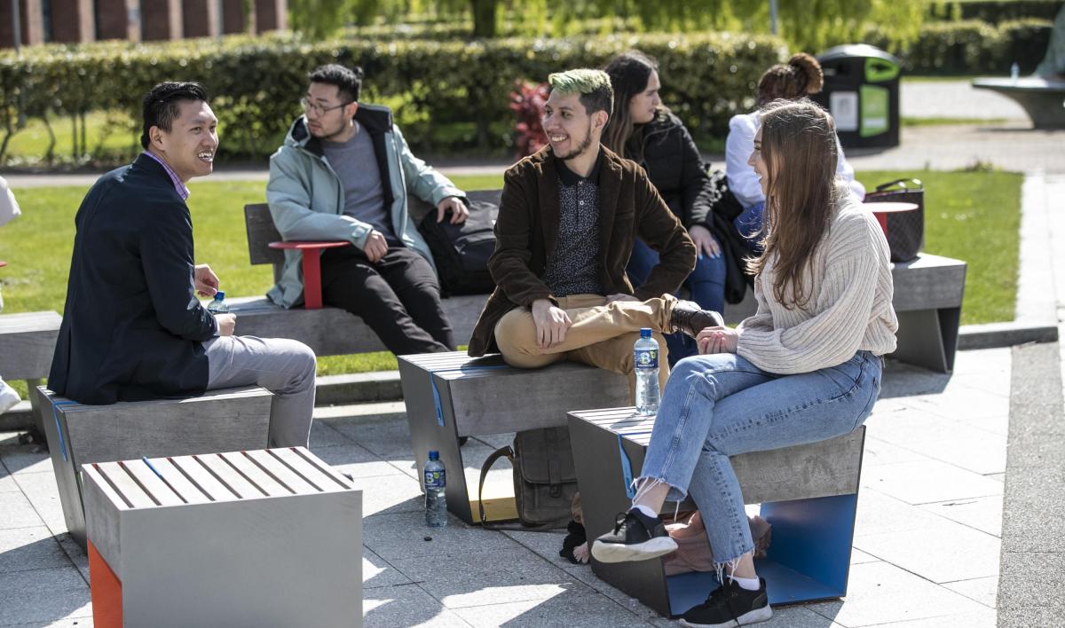 A group of international students sitting outside DCU in the sun