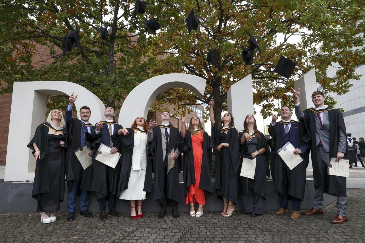 Some of our Global Business Graduates throwing their caps in front of the DCU sign to celebrate the day.