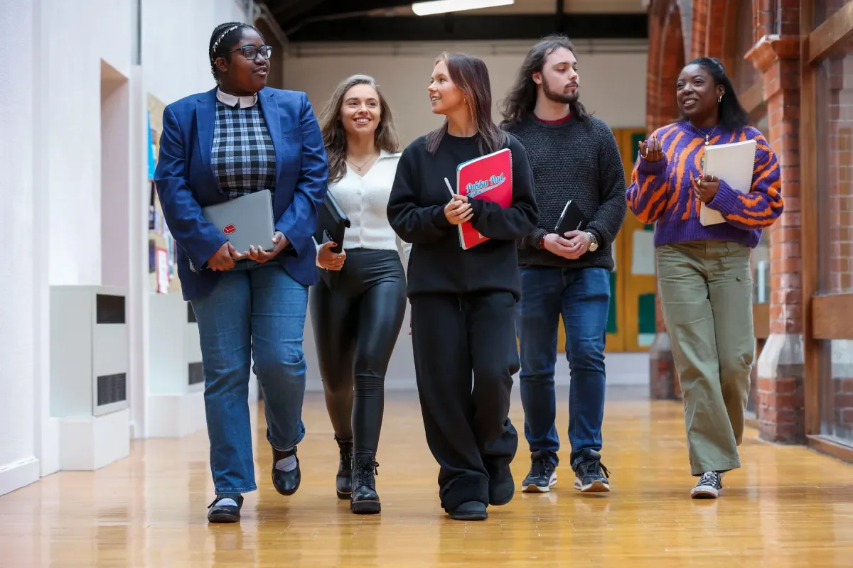 5 students walking in the university hallway.