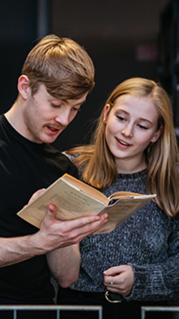 Two students chatting while looking at a book