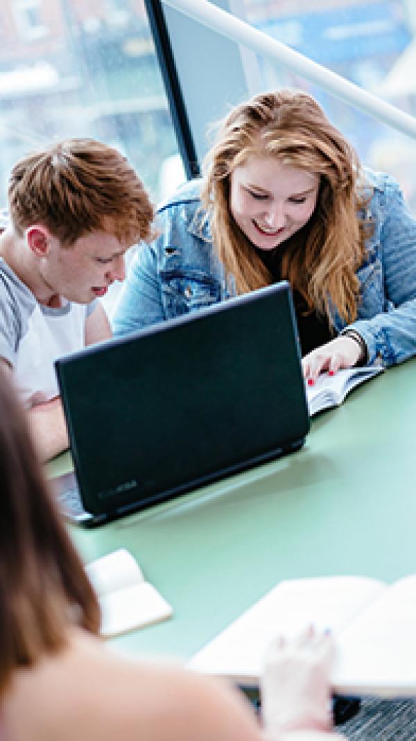 Two people chatting while looking at a computer