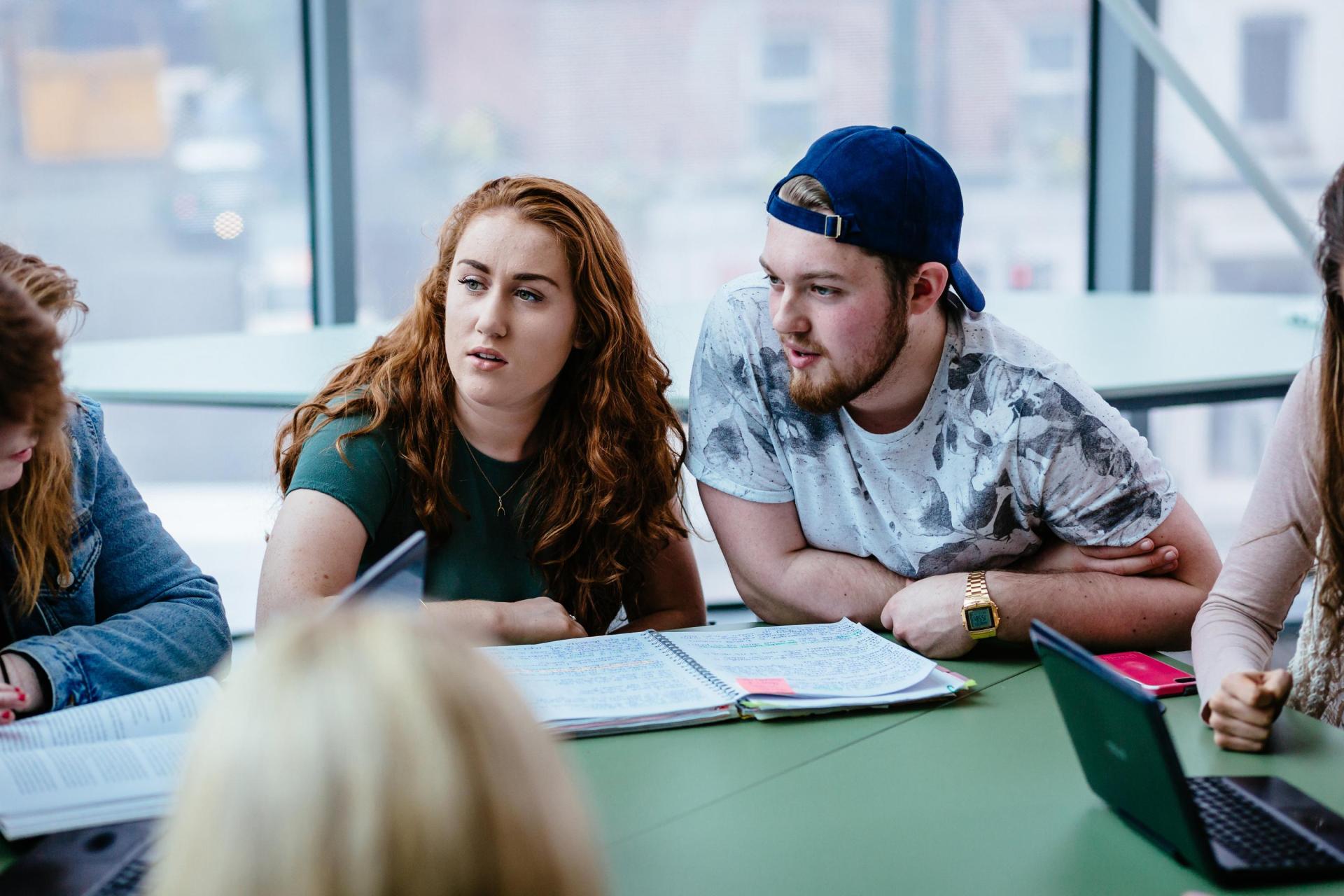Image of students studying around a desk.