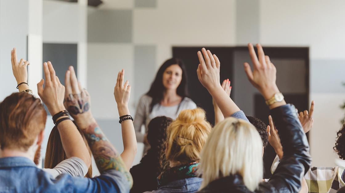 A group with raised hands at a seminar or conference.