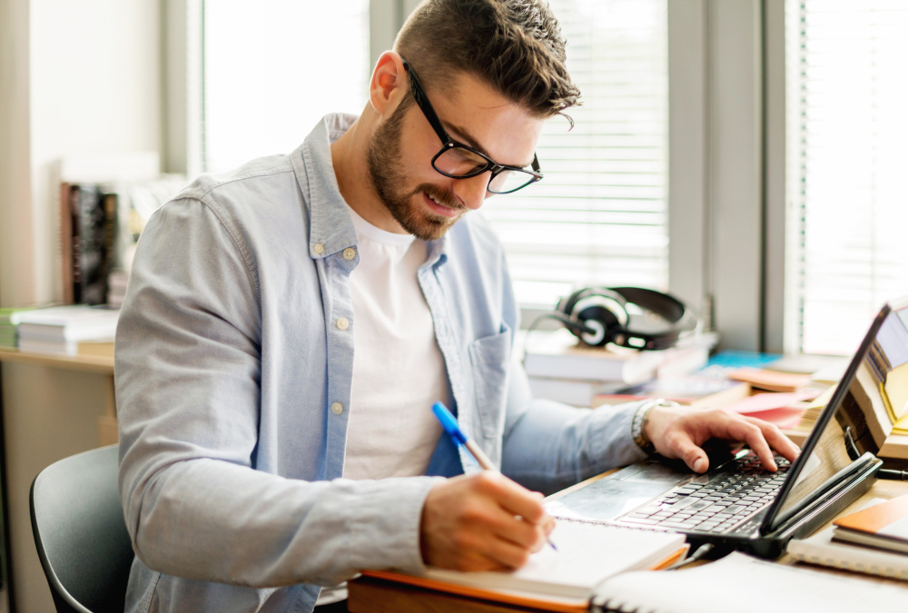 Male student writing at his laptop